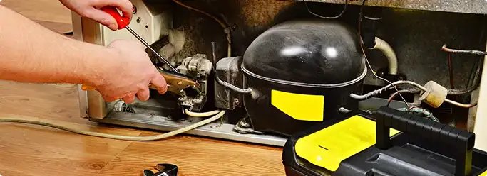 Refrigerator repair technician fixing the compressor and wiring in Lake Elmo, MN