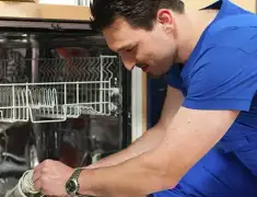 Dishwasher repair technician inspecting and servicing an open dishwasher in St Paul, MN