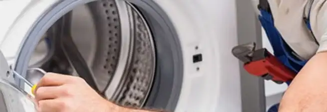 Appliance technician repairing a clothes dryer drum and internal parts in St Paul, MN