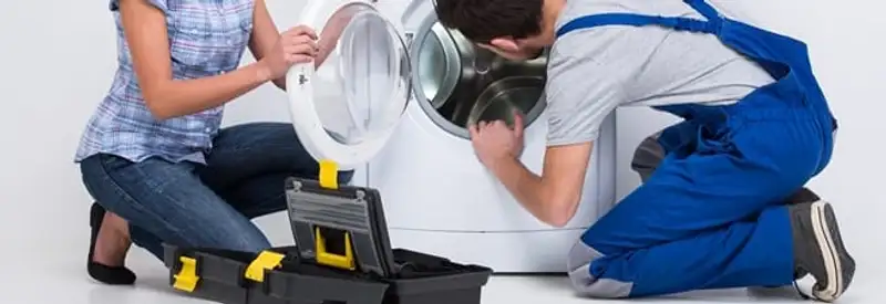 Washer repair technician inspecting a front-load washing machine with tools in St Paul, MN