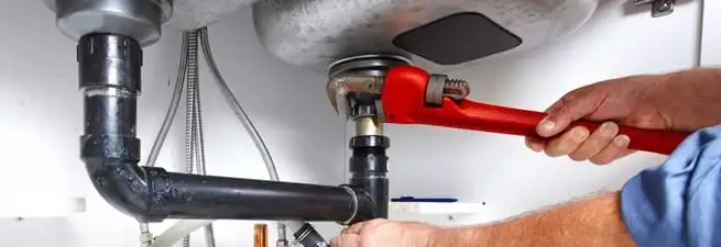 Garbage disposal repair technician tightening the sink drain and disposal connection in St Paul, MN