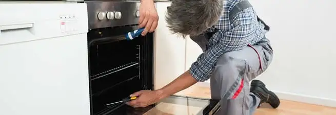Oven repair technician inspecting and servicing an electric oven in St Paul, MN