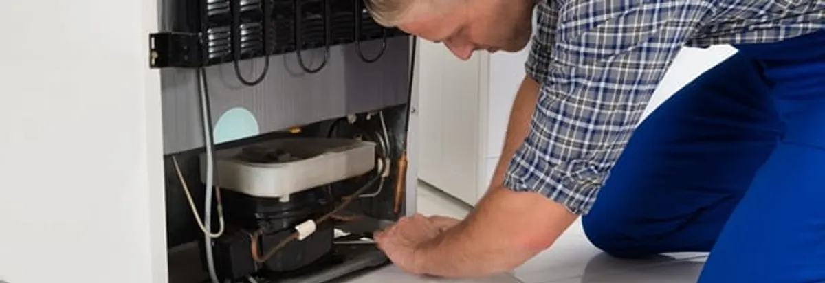 Refrigerator repair technician servicing the compressor and condenser area in St Paul, MN