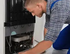 Refrigerator repair technician servicing the compressor and condenser area in St Paul, MN