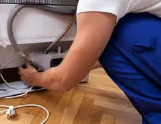 Appliance repair technician fixing refrigerator water line and connections in St Paul, MN