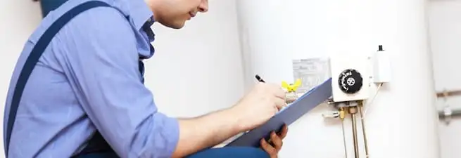 Water heater repair technician inspecting the unit and recording service notes in St Paul, MN